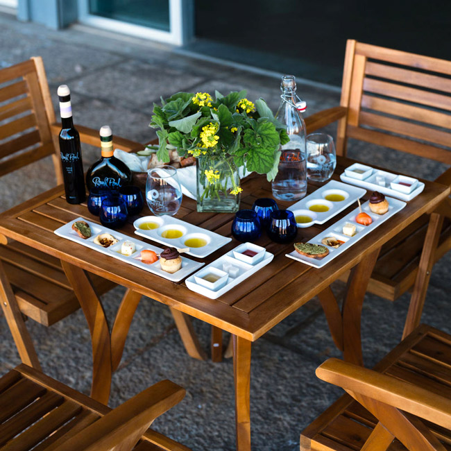 A table se for the Gourmet Tasting Experience at Round Pond Estate featuring sampling carafs and trays of estate olive oils, vinegars, and gourmet bites made.